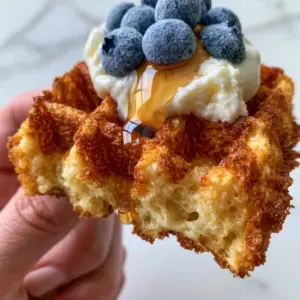 A handheld close-up shot pulling apart a Greek yogurt waffle to reveal a steaming, airy interior crumb.
