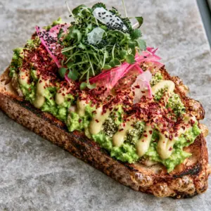 Close-up of vibrant green avocado mash with hemp hearts on charred sourdough bread. (vegan avocado toast)